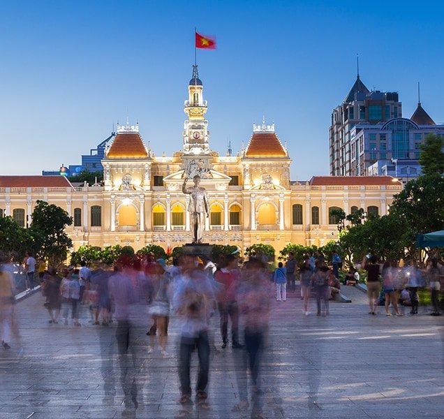 People are walking and taking pictures in front of the City Hall building, Ho Chi Minh City, Vietnam